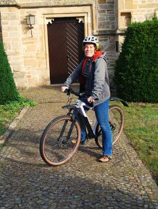 Pastoralreferentin Jessica Tomkin auf Entdeckertour mit dem Rad vor der alten Kirche in Mesum